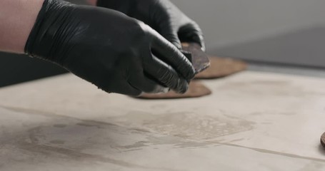 Wall Mural - Slow motion man hands applying oil finish on dark cork coaster