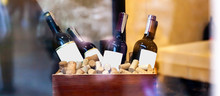 Wine Bottles With White Blank Labels In A Stylish Wooden Crate, Copy Space, Bottles Of Fine Wine Laying In A Box Of Corks On Display, Unbranded Mockup, Text Space, Product Shot, Winery Concept