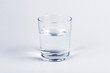 One simple half full half empty glass of fresh crystal clear clean drinking water, solo object isolated on light blue background. Hydration and health symbol, minimal, minimalistic concept, closeup