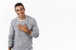 Happy and pleased, flattered hispanic man thanking for praises, holding hand on chest and smiling grateful, saying my pleasure, express gratitude and delighted, white background