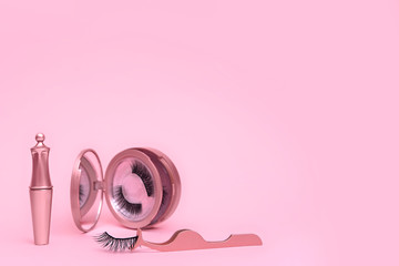 Wall Mural - Magnetic fake eyelashes in pink mirror kit, eye liner, tweezers isolated on pink background. Eyelash extension tool concept, beauty treatment, improving physical appearance. Soft selective focus