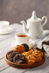 Wall Mural - Set of different cookies in a plate and tea on a wooden background.