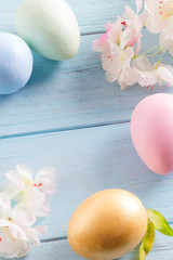 Wall Mural - Close-up greeting Easter card from handcraft painted eggs and tenter flowers on a light blue wooden background.