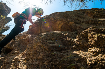 Wall Mural - A rock climber climbs on a yellow rock in the glare of the sun, view from below.