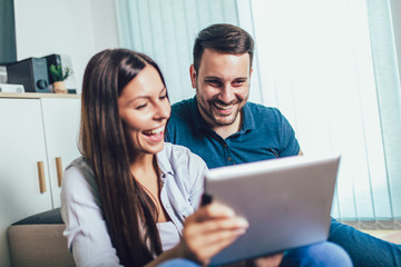 Happy young couple enjoying time online on digital tablet.