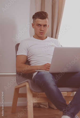 Cuadros en Lienzo Handsome young man sitting and working on laptop computer