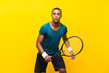 Afro American tennis player man over isolated yellow background