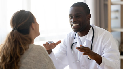 Smiling African American doctor consulting female patient at meeting