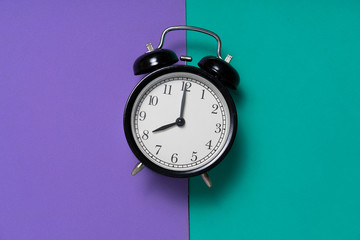 Wall Mural - Retro alarm clock on purple and green table baclground, vintage style time concept