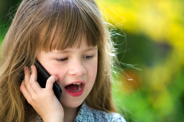 Cute child young girl talking on cellphone outdoors. Children and modern technology, communication concept.