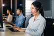 © anon - Asian confidence operator woman agent with headsets working in a call center at night Environment with her colleague team as customer service.Successful business people in headsets are using gadgets .