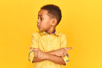 Wall Mural - Isolated image of stressful African American schoolboy being nervous because can't show right direction, looking for way home after he got lost, pointing fingers. Navigation and spatial orientation