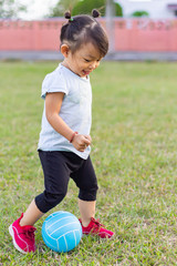 Wall Mural - Happy Asian baby child girl playing and​ holding a​ ball toys at the field playground. 