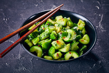 Wall Mural - Smashed Cucumber salad in a black bowl