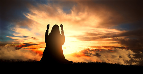 silhouette of a Muslim woman praying at sunset