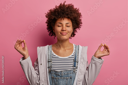 Cuadros en Lienzo Portrait of relieved determined dark skinned woman meditates with closed eyes, p
