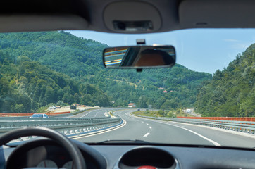 Asphalt highway through a picturesque landscape seen from a car in motion