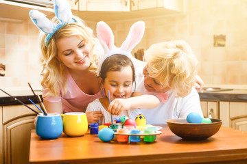 Wall Mural - little girl in a rabbit costume prepares for Easter and paints eggs