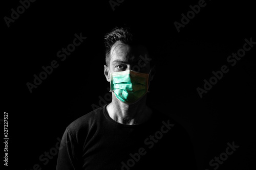 Portrait of  sick caucasian man with medical mask. Coronavirus Covid-19 concept. Black background.  Black and white