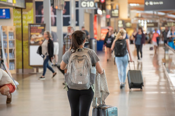 A young woman pulls her carry on luggage through an airport