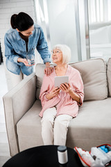 Wall Mural - Young woman giving glass of water to smiling grandmother