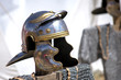 Close up view of a Roman helmet with come chain mail appearing underneath it placed on top of a wood strut