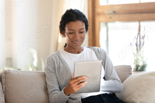 Fotomural Happy african American woman browsing internet on tablet gadget