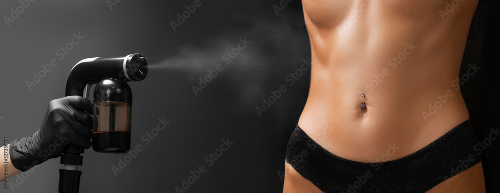 Spray tan airbrush woman body paint in professional beauty salon - obrazy, fototapety, plakaty 