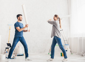 Wall Mural - Happy young couple fighting with rollers and smiling each other