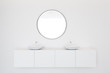Double sink in white bathroom with round mirror