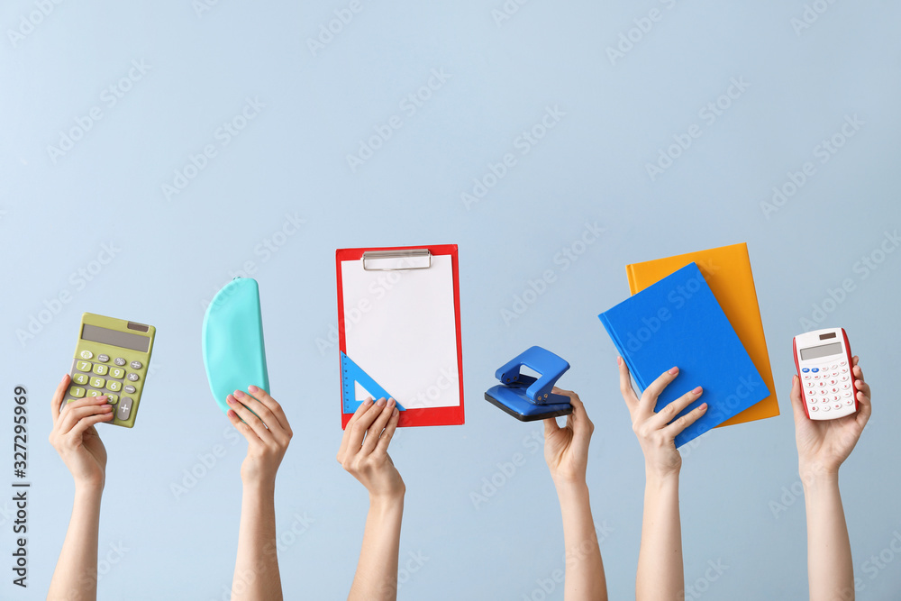 Many hands with school supplies on color background