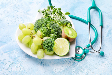 Wall Mural - Plate with healthy products and stethoscope on color background