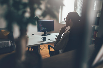 young woman working at his home office . rear view of programmer reading computer codes on desktop p