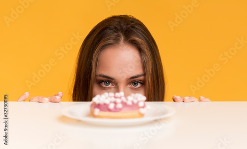 Fotografía Hungry Woman Peeking Out Of Table Starving To Eat Donut
