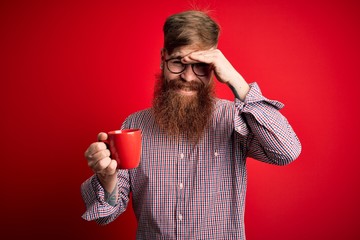 Sticker - Redhead Irish man with beard drinking a cup of hot coffee over red background stressed with hand on head, shocked with shame and surprise face, angry and frustrated. Fear and upset for mistake.