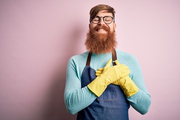 Poster - Irish redhead housekeeping man with beard wearing apron and washing gloves smiling with hands on chest with closed eyes and grateful gesture on face. Health concept.