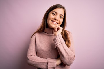 Sticker - Beautiful young woman wearing turtleneck sweater over pink isolated background looking confident at the camera with smile with crossed arms and hand raised on chin. Thinking positive.