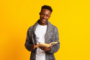 Wall Mural - Smiling young african guy reading book for education
