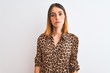 © Krakenimages.com - Beautiful redhead woman wearing elegant animal print shirt over isolated background with serious expression on face. Simple and natural looking at the camera.
