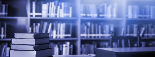 Poster - Stack of books in the library and blur bookshelf background	