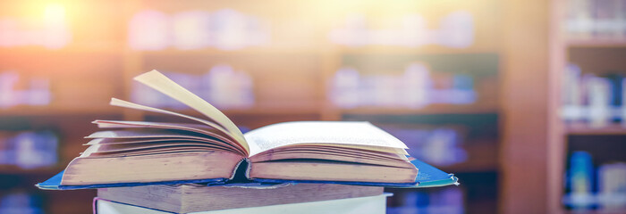 Poster - Stack of books in the library and blur bookshelf background	