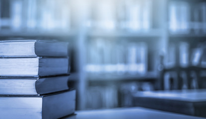 Poster - Stack of books in the library and blur bookshelf background	