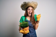 Young Beautiful Redhead Farmer Woman Wearing Apron And Hat Holding Plant Pot Screaming Proud And Celebrating Victory And Success Very Excited, Cheering Emotion