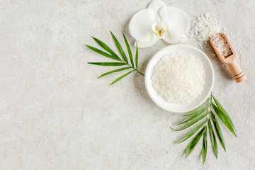 Spa treatment concept. Natural/Organic spa cosmetics products, sea salt and tropic palm leaves on gray marble table from above. Spa background with a space for a text, flat lay, top view.