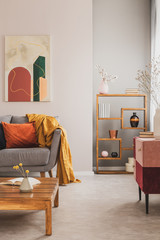 Wall Mural - Fancy wooden bookshelf with vases and boxes next to grey scandinavian couch