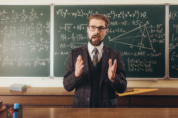 young handsome academic in suit and glasses teaching geometry during college lecture