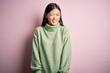 © Krakenimages.com - Young beautiful asian woman wearing green winter sweater over pink solated background winking looking at the camera with sexy expression, cheerful and happy face.