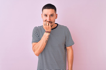 Sticker - Young handsome man wearing striped t-shirt standing over pink isolated background looking stressed and nervous with hands on mouth biting nails. Anxiety problem.