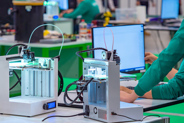 Poster - 3d printers are on the table. Teenagers set parameters for printing three-dimensional images. Technical circle with modern equipment. Layer-by-layer printing of objects using a 3d printer.