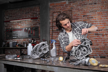 man work with the socket wrench, repair and cleaning engine parts on the workbench in home garage workshop, diy concept